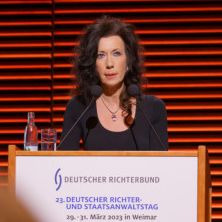 DRB-Vorsitzende Andrea Titz steht hinter einem Rednerpult und hälft die Eröffnungsrede auf dem 23. Deutsche Richter- und Staatsanwaltstag
